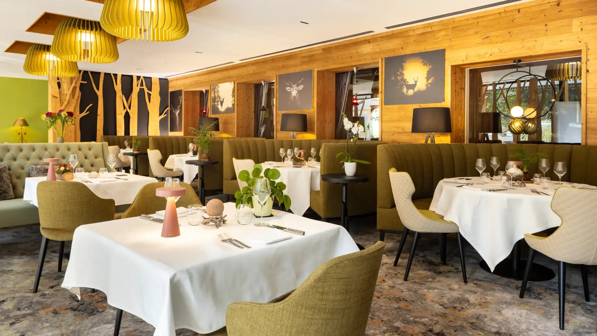 Elegant restaurant with set tables, green chairs, yellow lighting, and wooden walls