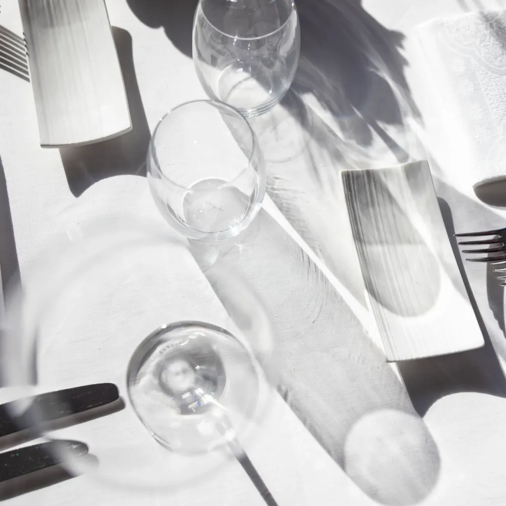 Table set with glasses, cutlery, and paper napkins in the sunlight