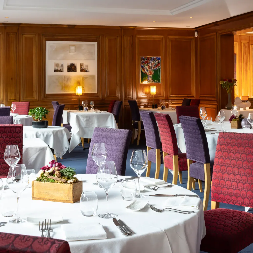 Elegant restaurant room with set tables, padded chairs, and artwork on the walls