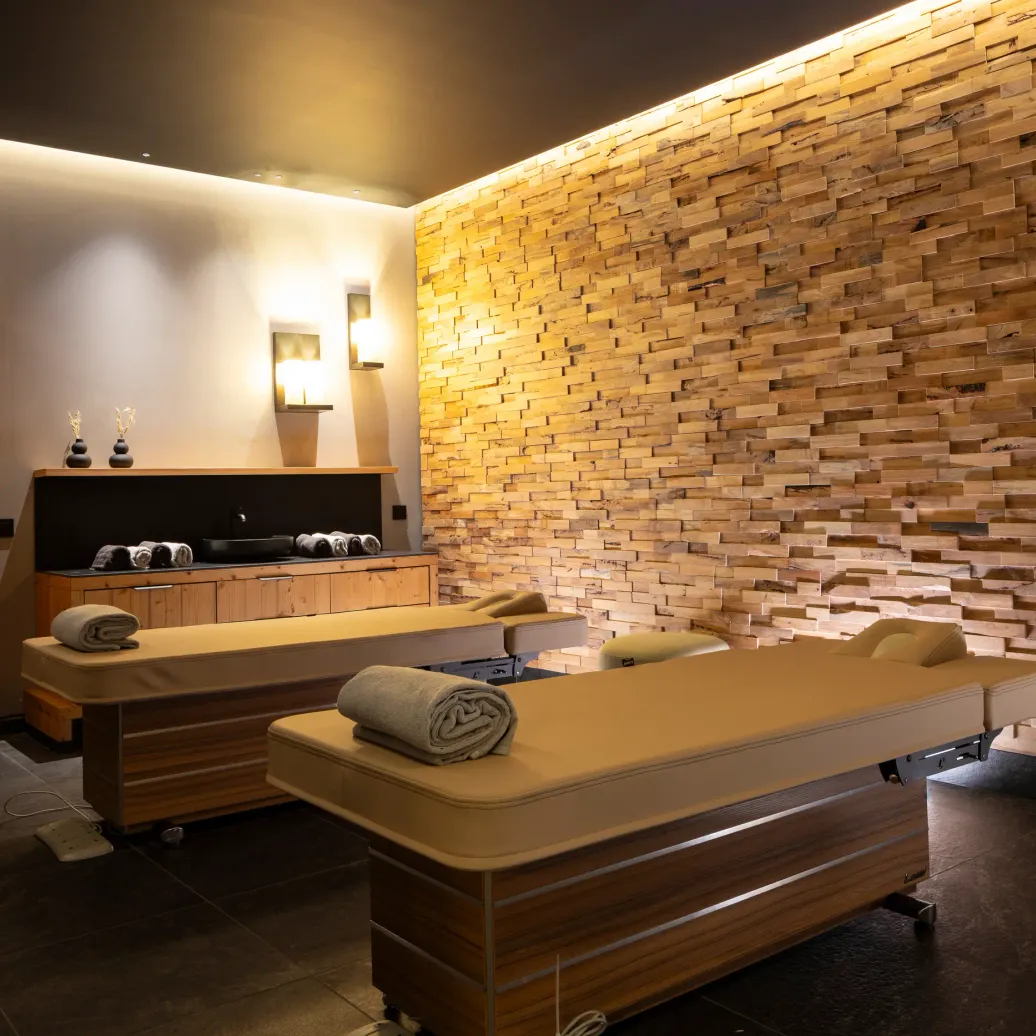 Massage room with two massage tables, exposed brick wall and rolled towels