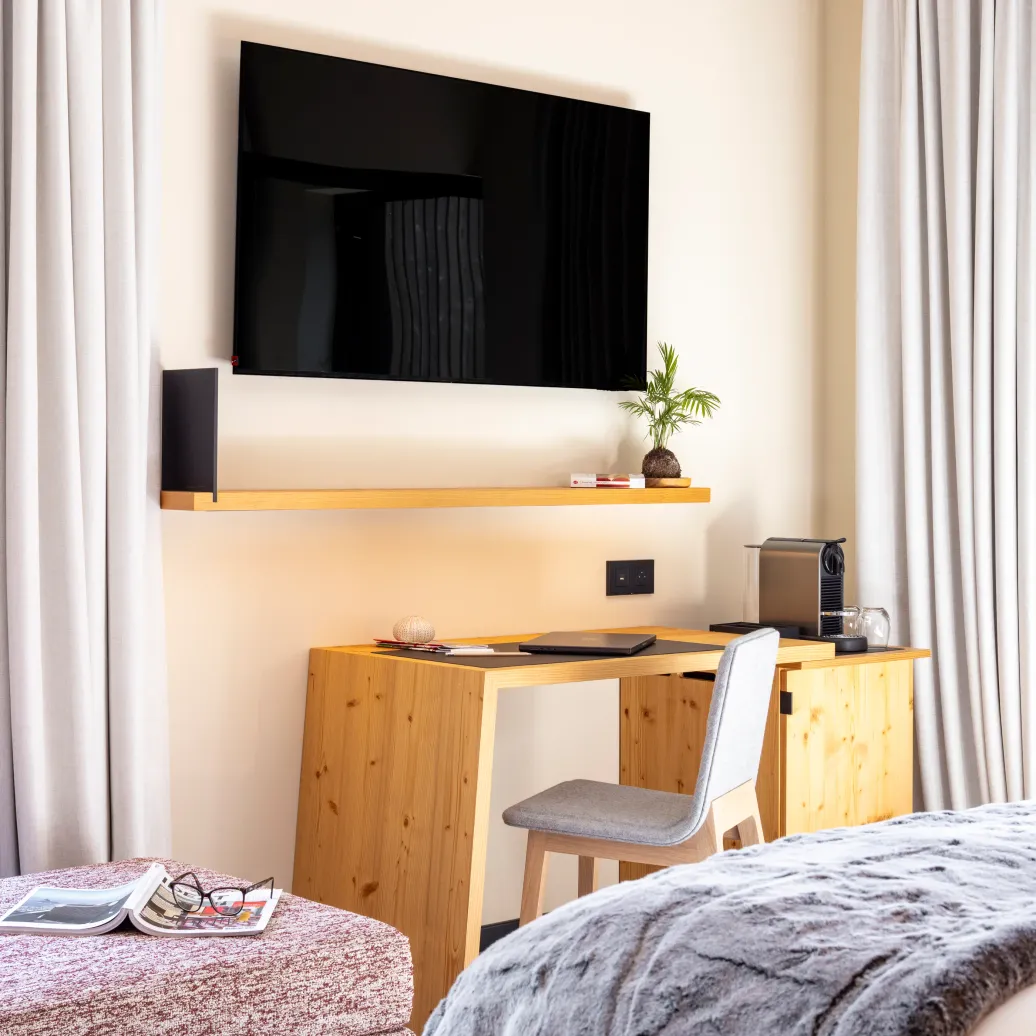 Room with a bed, a wooden desk, a television, and a coffee machine.