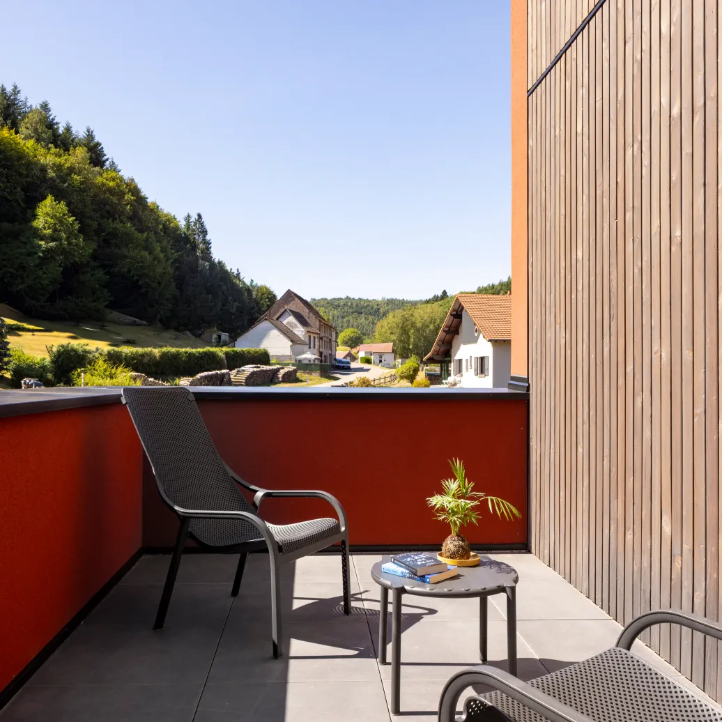 Balcon with three chairs and a coffee table, view of houses and wooded hills