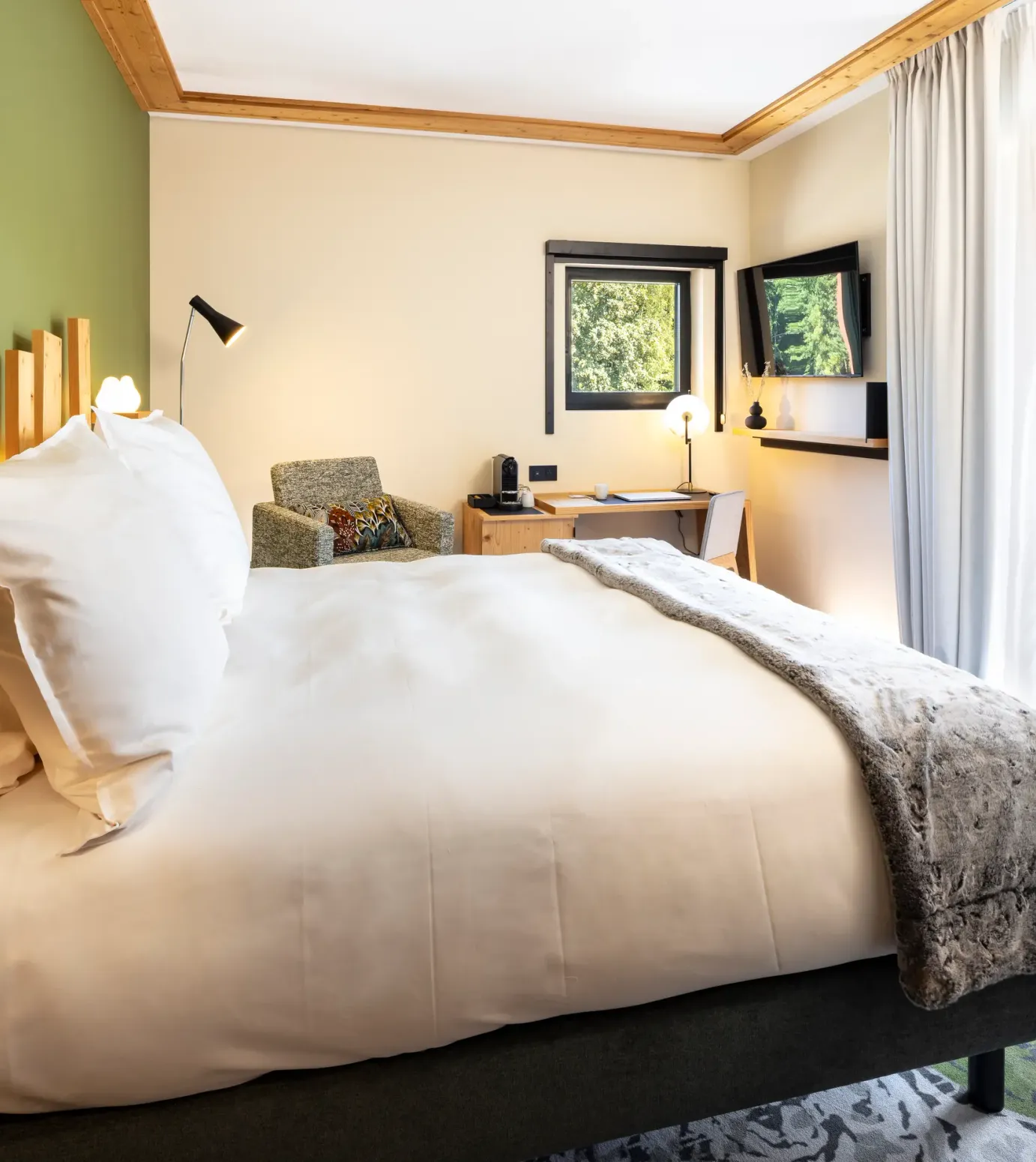 Room with a double bed, a bedside table, a desk, windows with an outside view, and a glass door leading to a balcony.