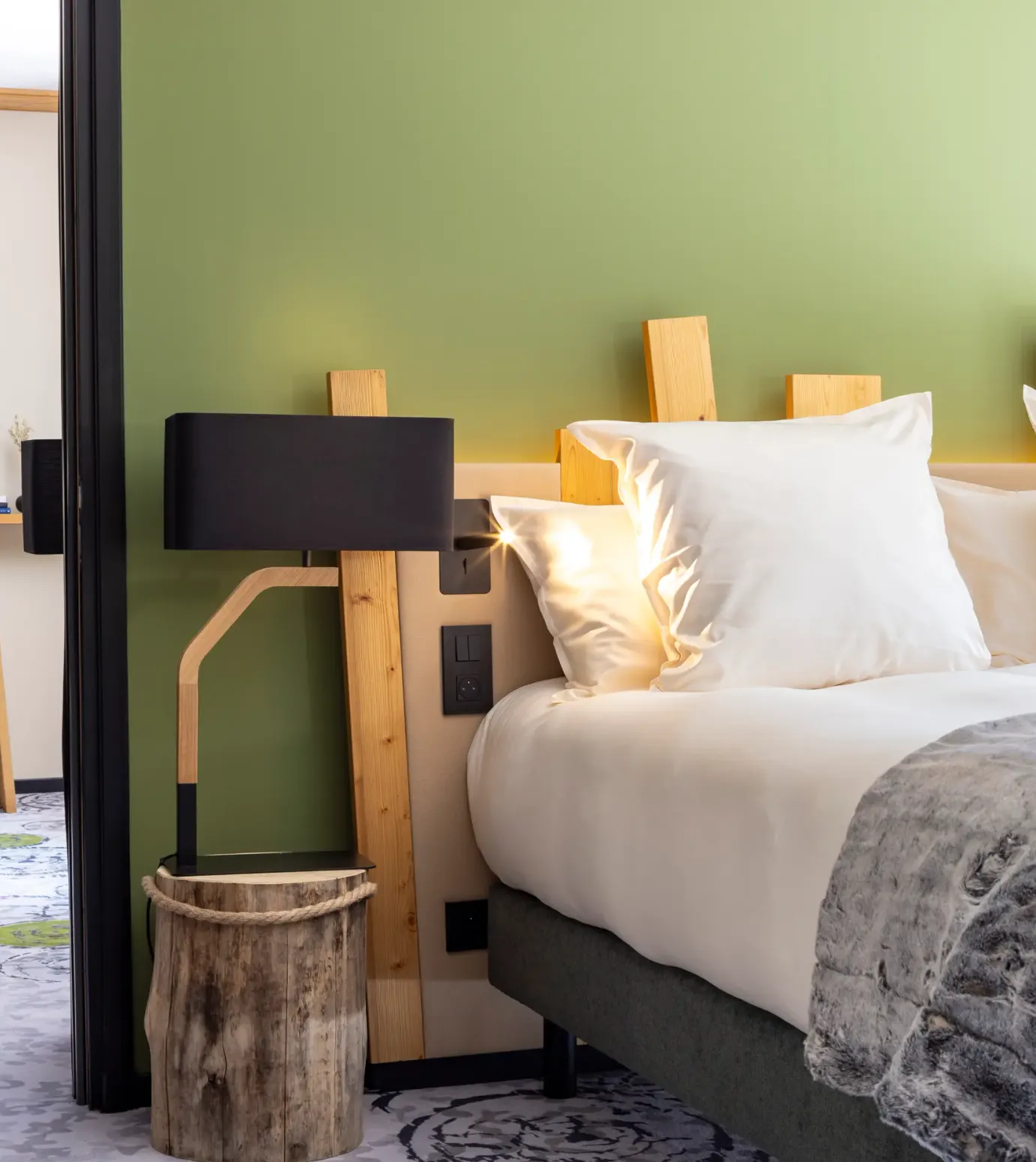 Hotelzimmer mit einem Doppelbett, einer Holz-Nachttischlampe, einem Fernseher und einem Schreibtisch mit einem Stuhl