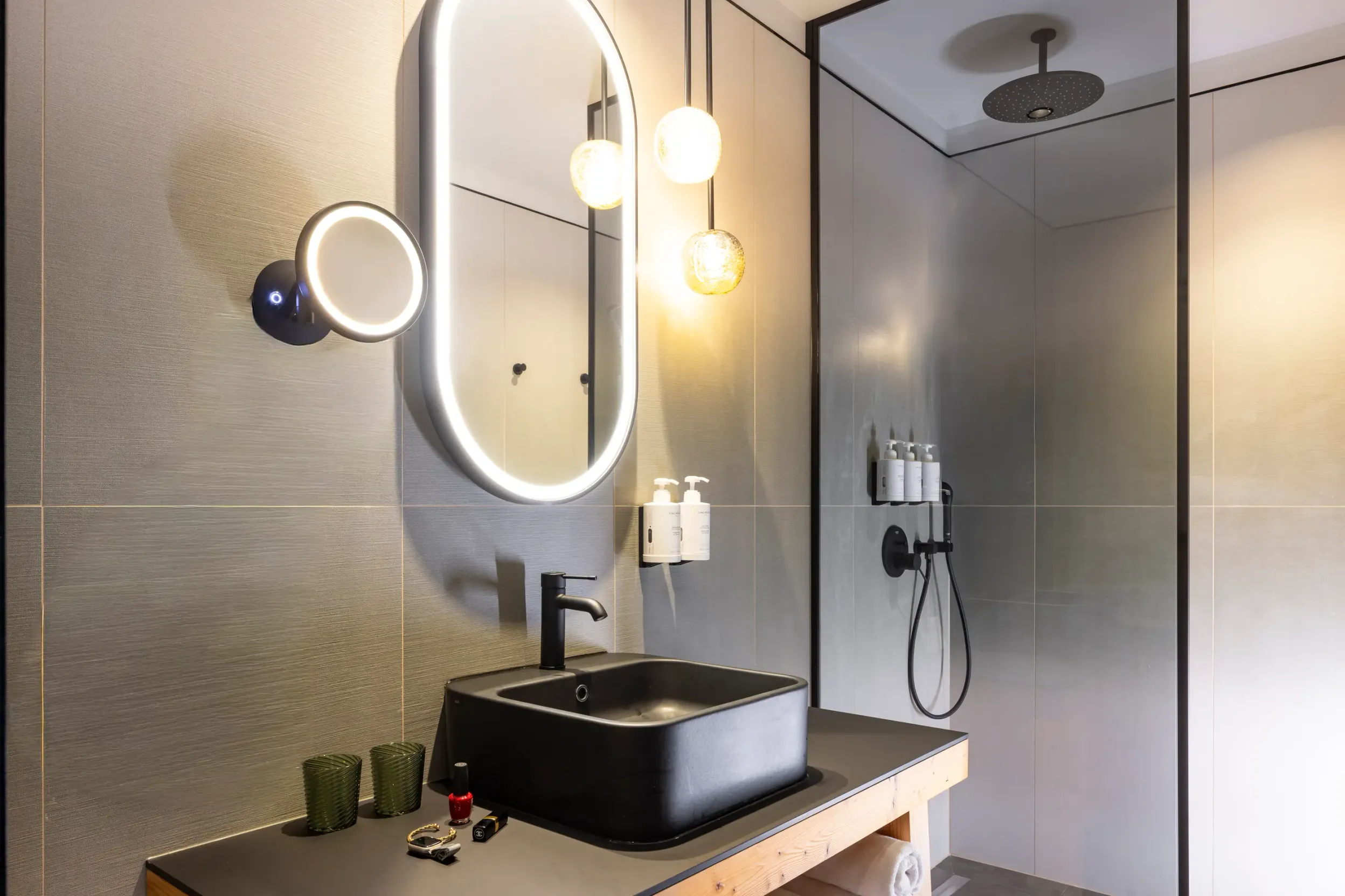 Salle de bain moderne avec lavabo noir, miroir ovale, douche à effet pluie et accessoires de toilette