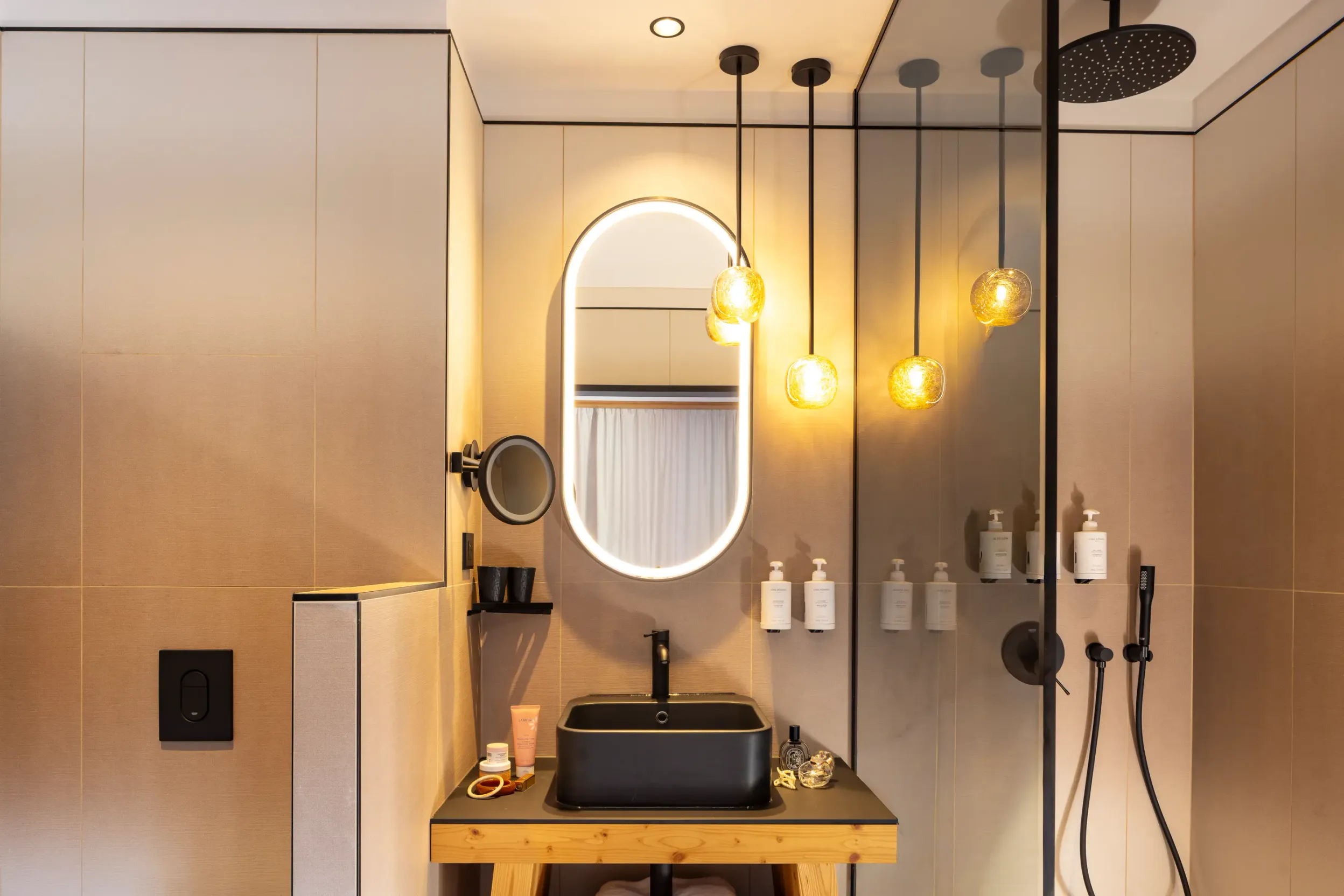Moderne Badezimmer mit schwarzem Waschbecken, ovalem Spiegel und Regendusche